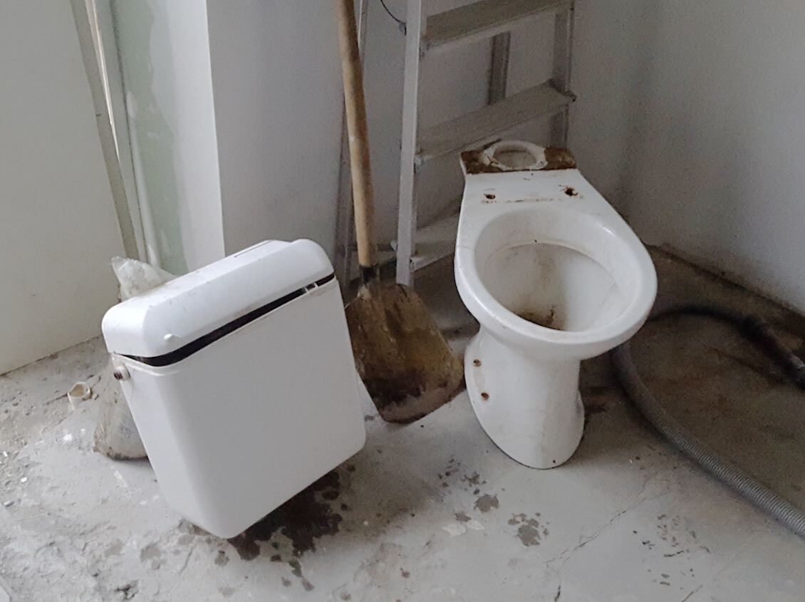 Afgebroken toilet in stukken gebroken op de grond